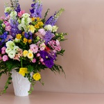 Bright bouquet in a vase with delphinium and peonies