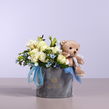 Flowers in a box in white and blue colors with a soft toy