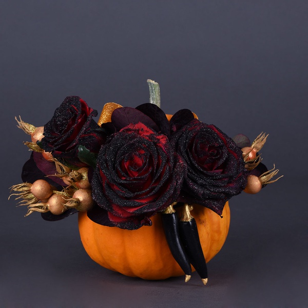 Floral composition with black roses in a pumpkin